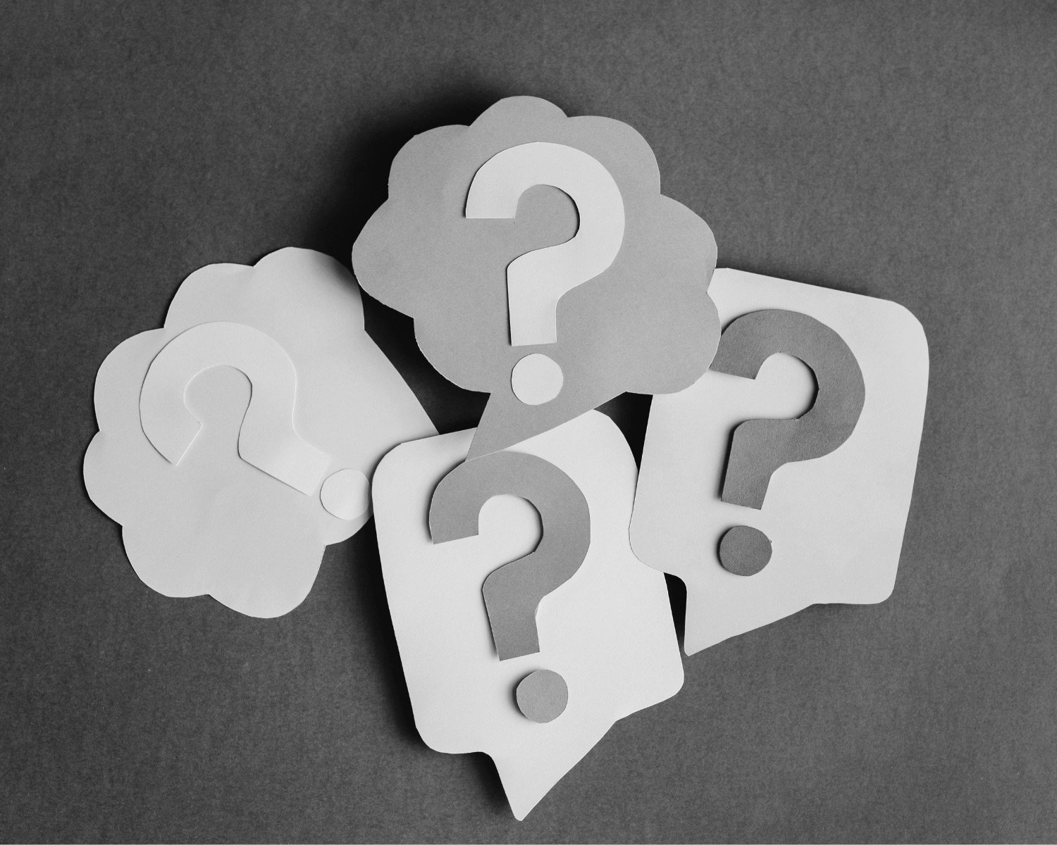 Paper cut-out speech bubbles each holding a question mark